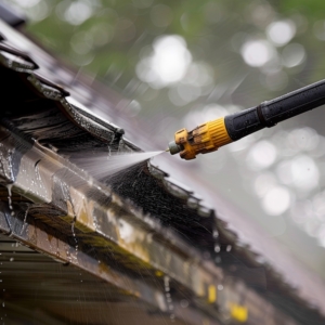 Close-up of meticulous cleaning of spring rain gutters with a pressure washer, highlighting